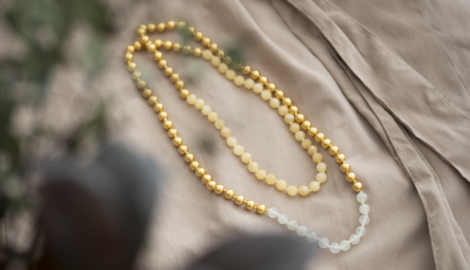 瑞々しいグリーンの影と、繊細な輝きを放つ箔座の箔珠ネックレス・ロング。自然体で上質な美しさ。